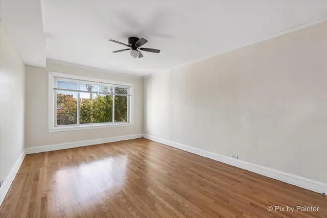 a view of empty room with wooden floor and fan