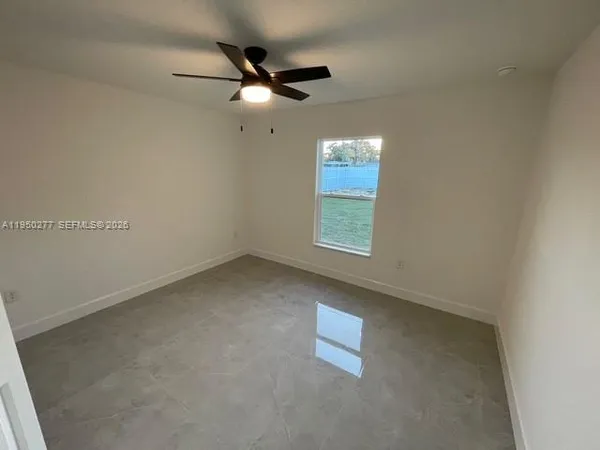 an empty room with a window and a fan