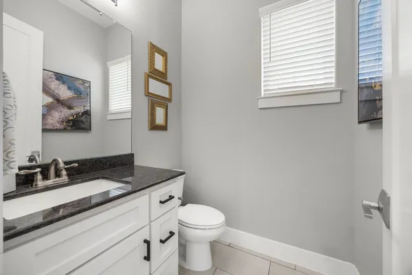 a bathroom with a granite countertop sink and a toilet