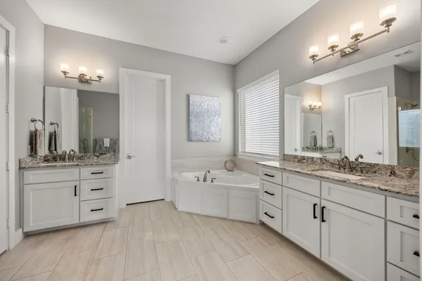 a spacious bathroom with double vanity a mirror a vanity and a bathtub