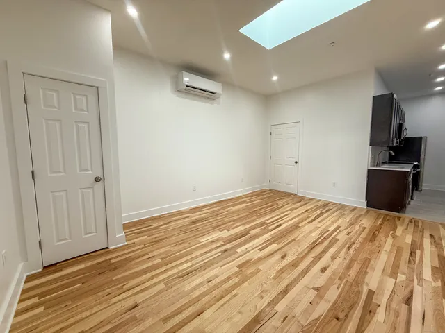 a view of a livingroom with wooden floor and kitchen