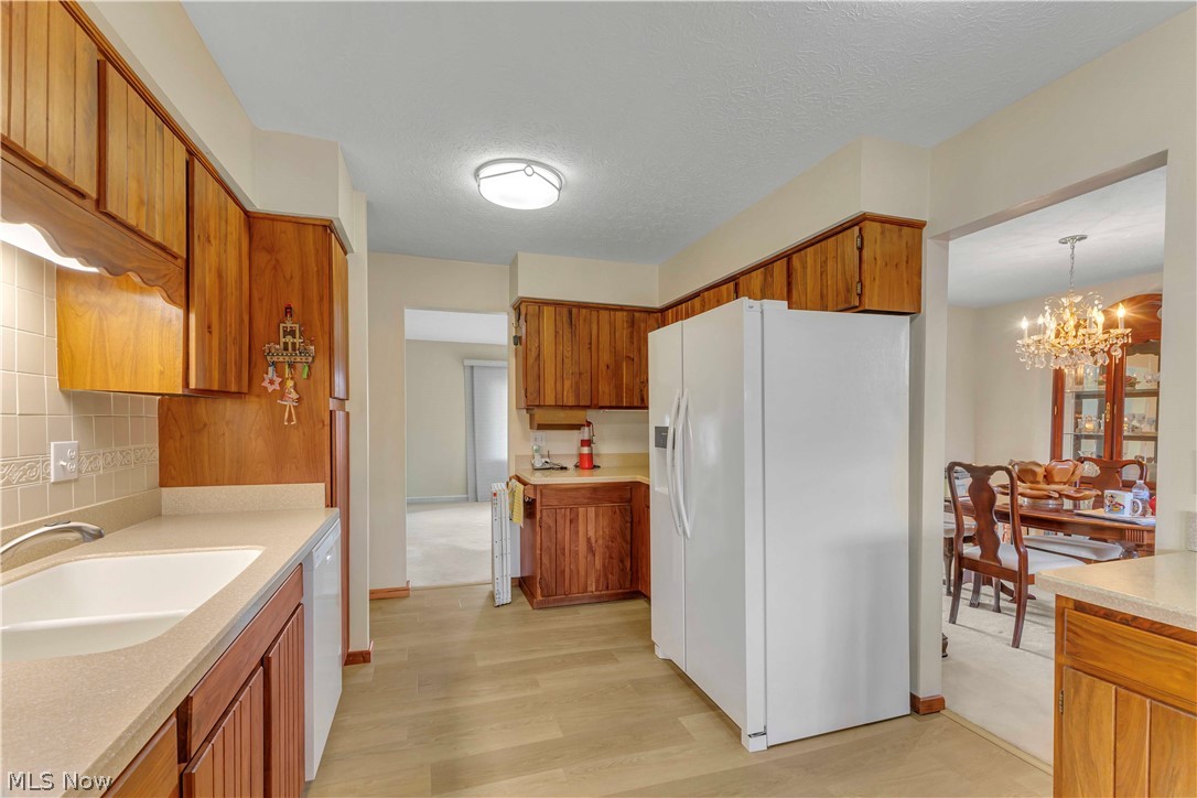 563 North Carpenter Road Brunswick, OH 44212 - Photo 10 of 45 Kitchen with wood finish cabinetry, white appliances, light wood-style flooring, and a textured ceiling