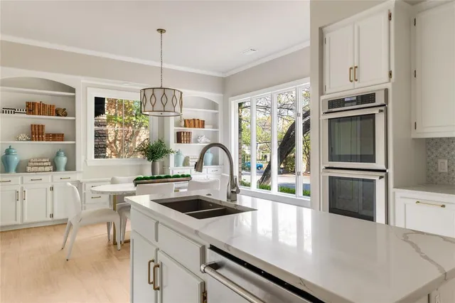 a kitchen with stainless steel appliances a stove a sink a microwave and white cabinets