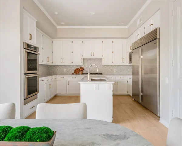 a kitchen with white cabinets a sink stove and refrigerator