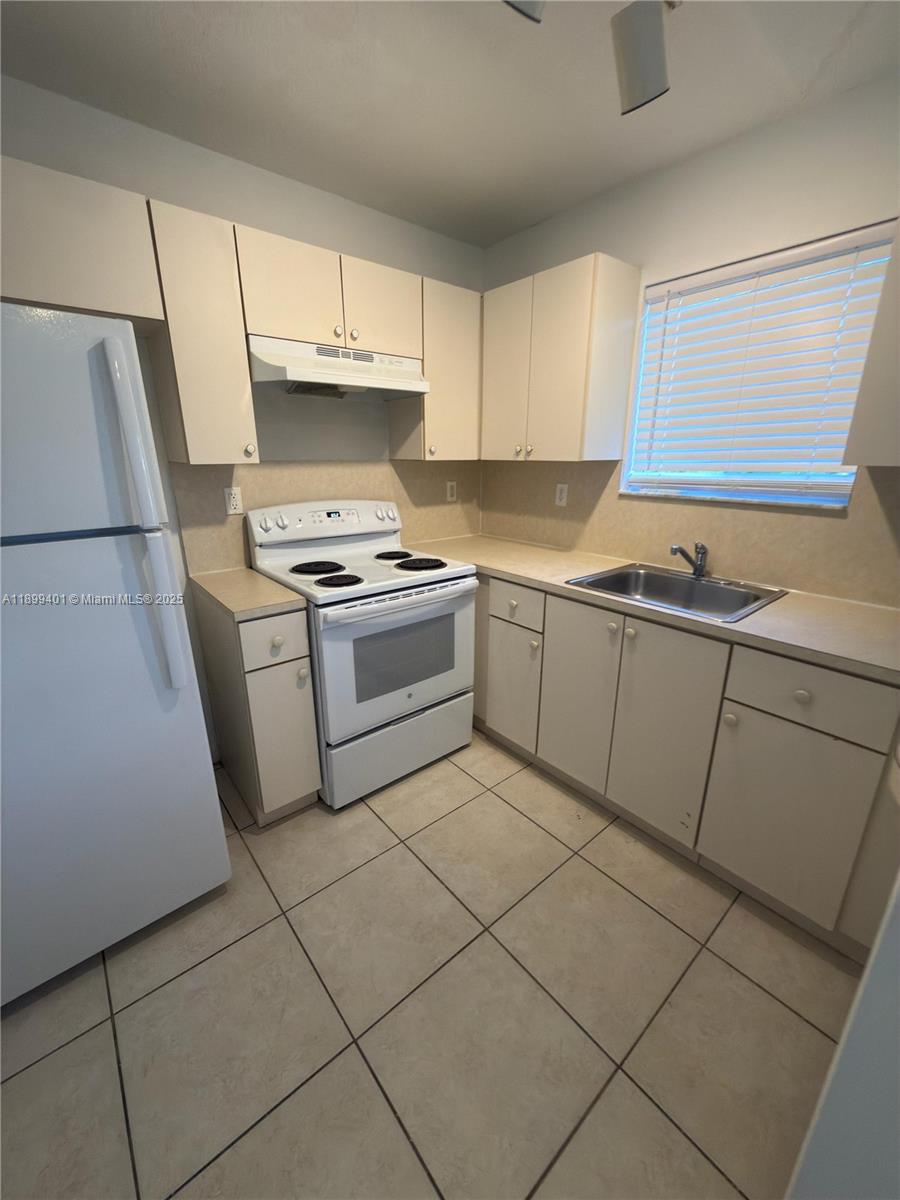930 Northeast 34th Avenue, Unit 201 Homestead, FL 33033 - Photo 12 of 26 a kitchen with cabinets and white appliances