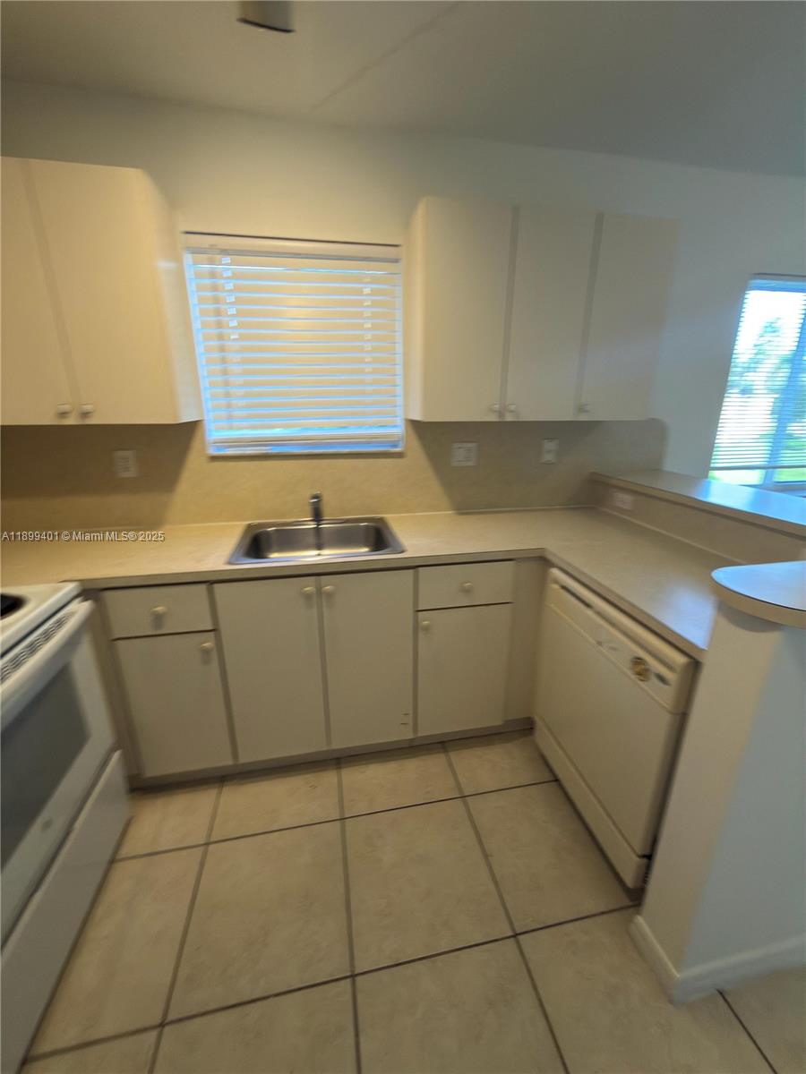930 Northeast 34th Avenue, Unit 201 Homestead, FL 33033 - Photo 14 of 26 a kitchen with a sink a stove top oven and cabinets