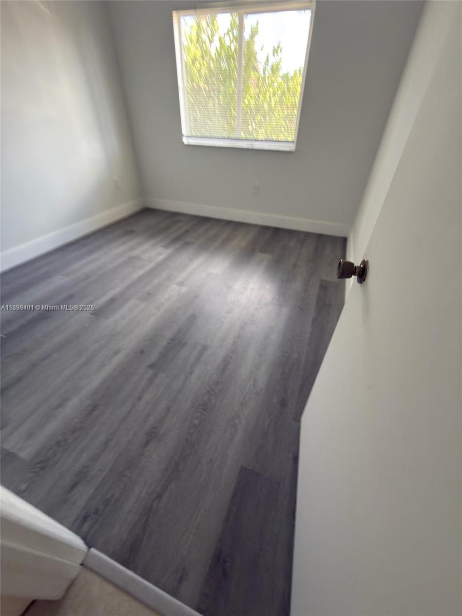 930 Northeast 34th Avenue, Unit 201 Homestead, FL 33033 - Photo 20 of 26 an empty room with wooden floor and windows