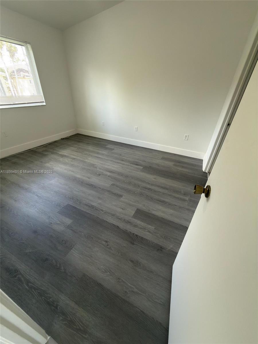 930 Northeast 34th Avenue, Unit 201 Homestead, FL 33033 - Photo 22 of 26 a view of an empty room with wooden floor and a window