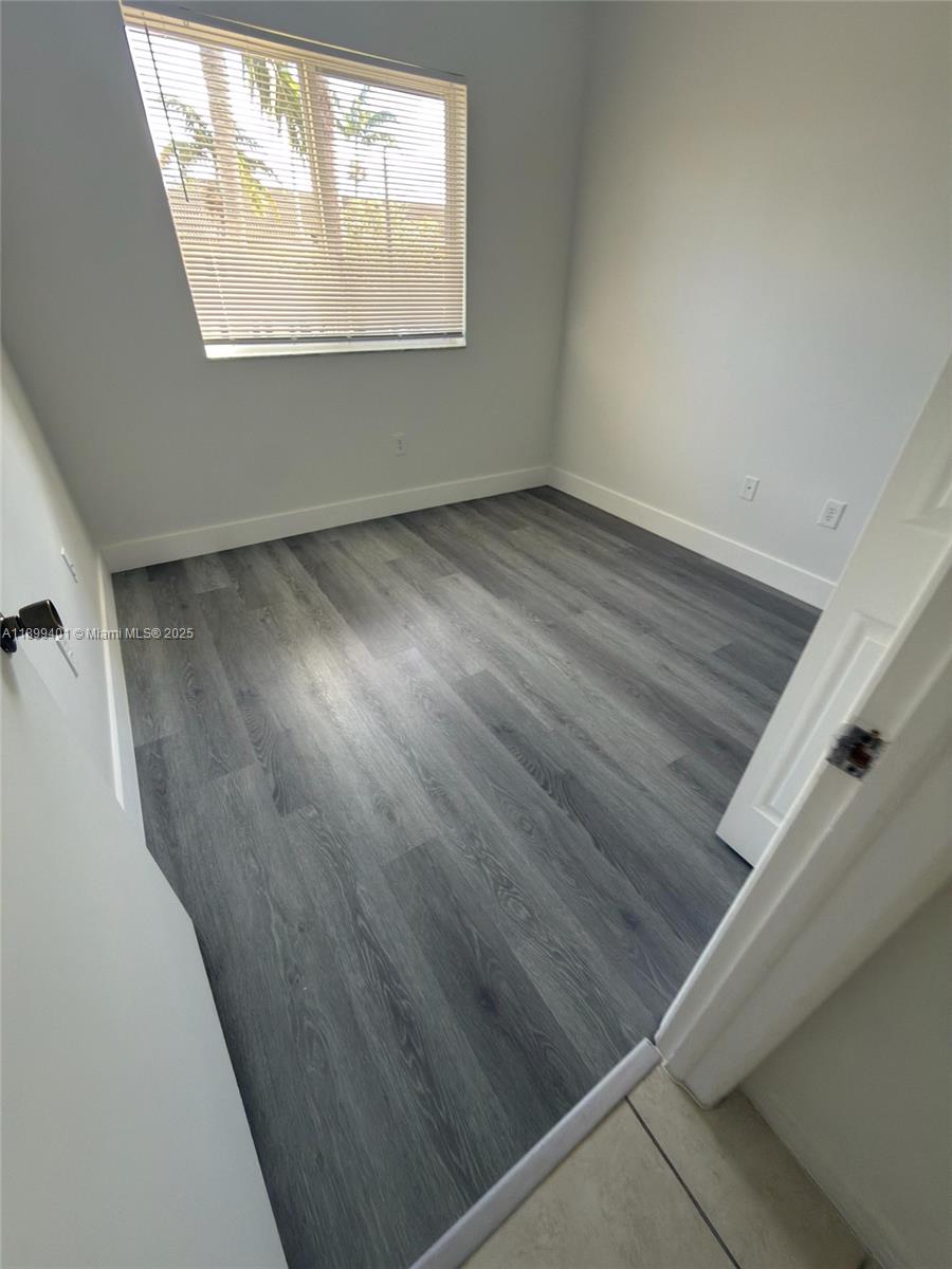 930 Northeast 34th Avenue, Unit 201 Homestead, FL 33033 - Photo 24 of 26 an empty room with wooden floor and windows
