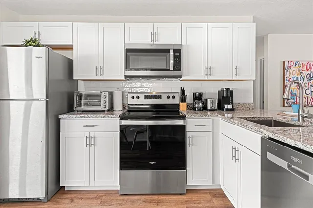 a kitchen with white cabinets and stainless steel appliances