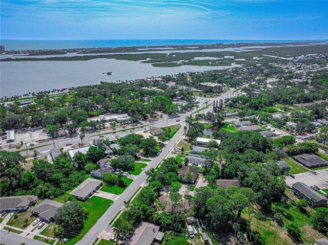 an aerial view of a city with lots of residential buildings ocean and mountain view in back