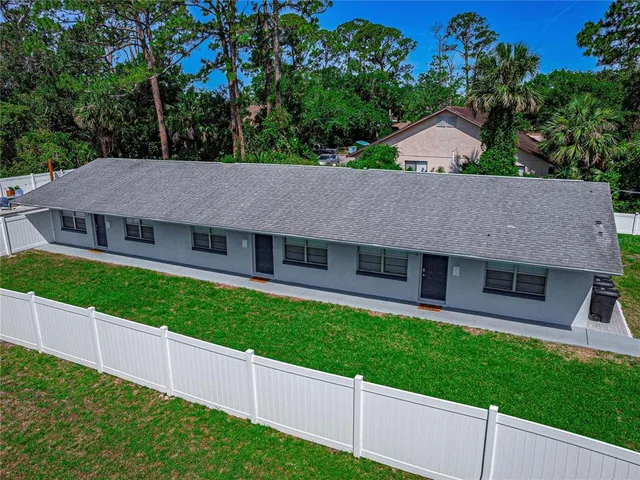 a aerial view of a house next to a yard and large tree