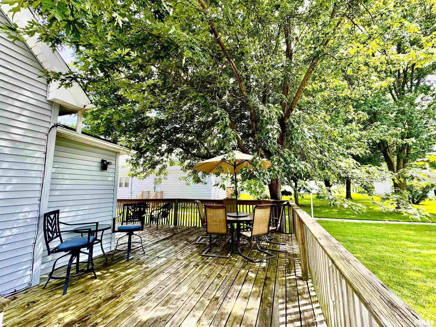 1215 13th Street Viola, IL 61486 - Photo 4 of 35 a view of a patio with table and chairs under an umbrella with large trees
