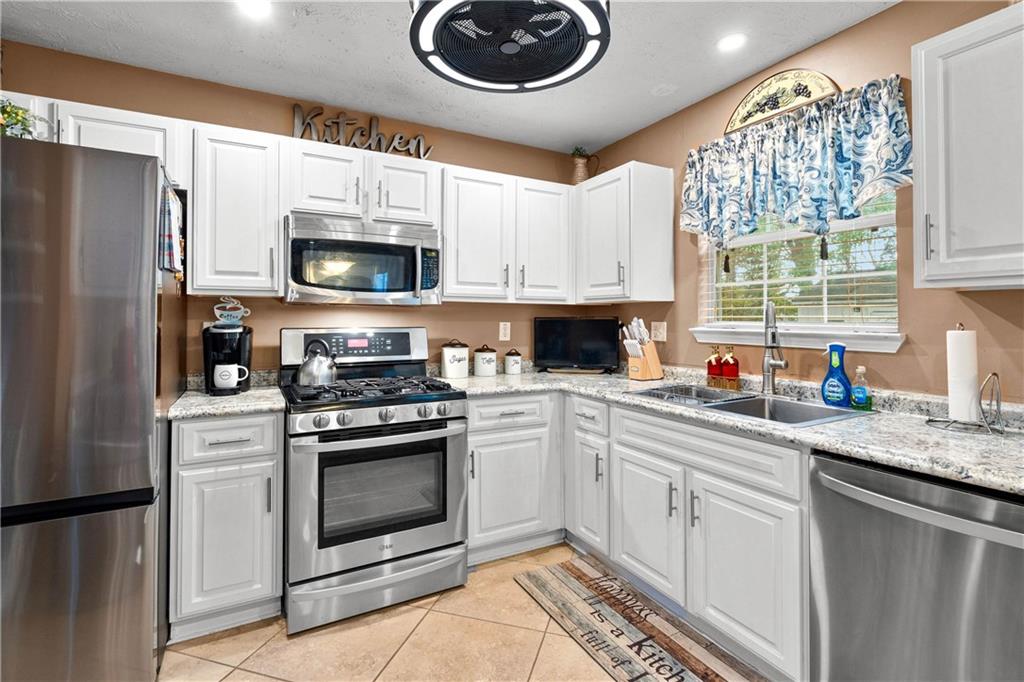 1380 Pebble Beach Lane Hampton, GA 30228 - Photo 18 of 59 a kitchen with stainless steel appliances granite countertop a sink a stove a microwave a refrigerator and cabinets