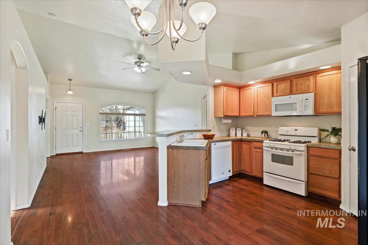 612 Goshawk Avenue Middleton, ID 83644 - Photo 10 of 36 Kitchen featuring white appliances, a peninsula, vaulted ceiling, a chandelier, and a ceiling fan