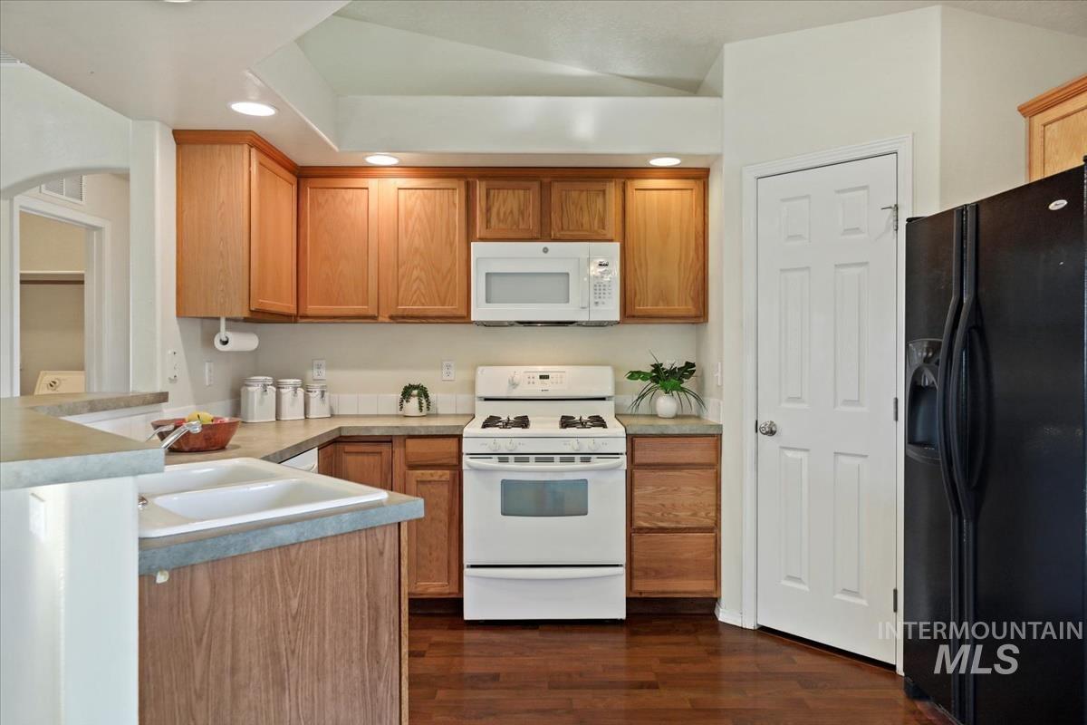 612 Goshawk Avenue Middleton, ID 83644 - Photo 13 of 36 Kitchen with white appliances, wood finish cabinetry, recessed lighting, light countertops, and dark wood-style flooring