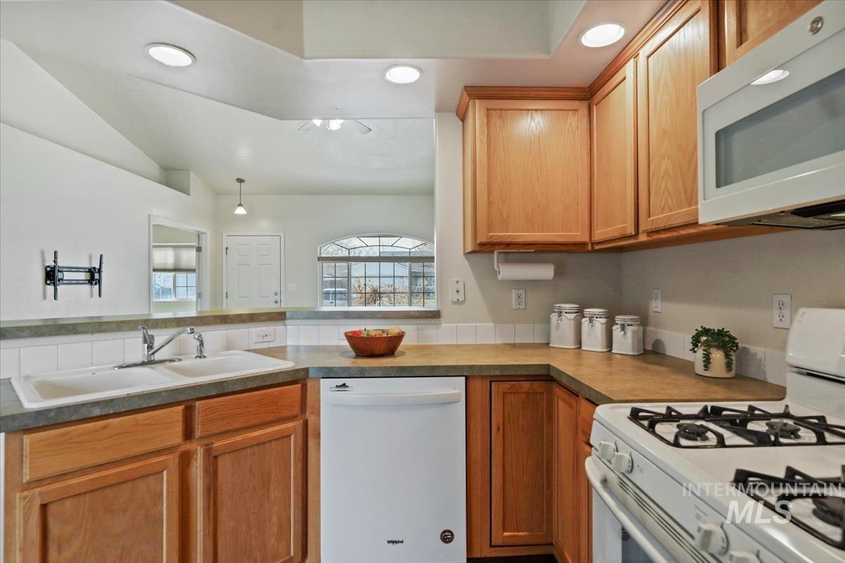 612 Goshawk Avenue Middleton, ID 83644 - Photo 15 of 36 Kitchen featuring white appliances, wood finish cabinetry, vaulted ceiling, light countertops, and recessed lighting