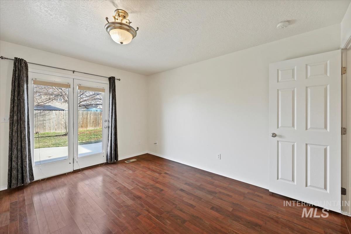 612 Goshawk Avenue Middleton, ID 83644 - Photo 17 of 36 Empty room featuring a textured ceiling and dark wood-style floors