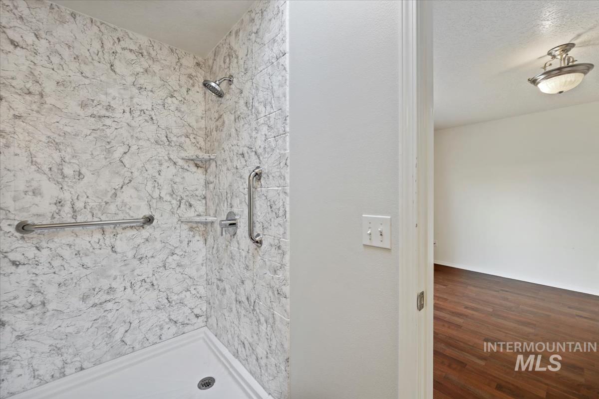 612 Goshawk Avenue Middleton, ID 83644 - Photo 19 of 36 Full bathroom featuring a marble finish shower and dark wood-style flooring