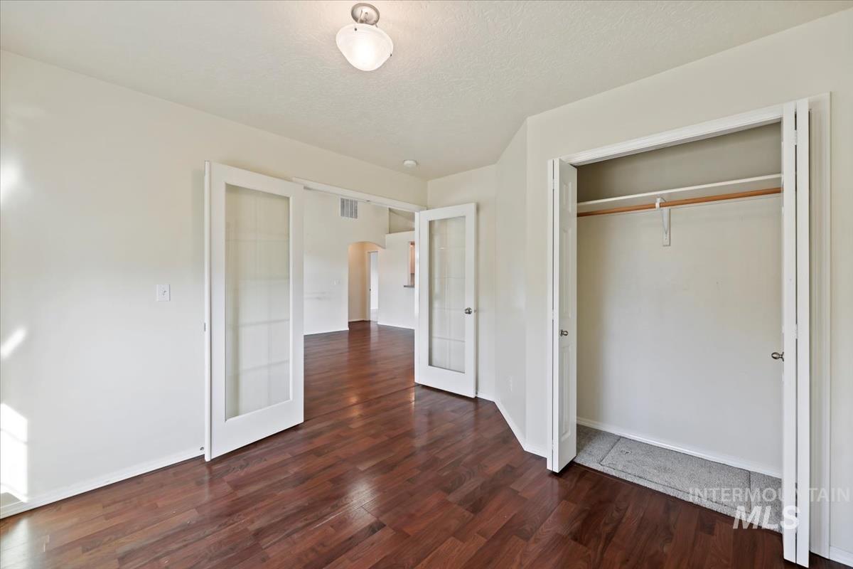 612 Goshawk Avenue Middleton, ID 83644 - Photo 28 of 36 Unfurnished bedroom featuring dark wood-style floors, french doors, a closet, a textured ceiling, and arched walkways