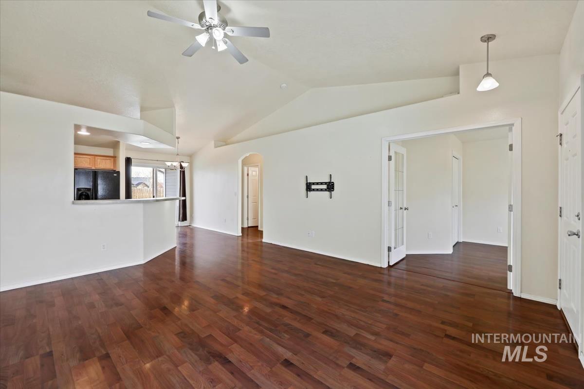 612 Goshawk Avenue Middleton, ID 83644 - Photo 4 of 36 Unfurnished living room featuring arched walkways, ceiling fan, dark wood-type flooring, and vaulted ceiling