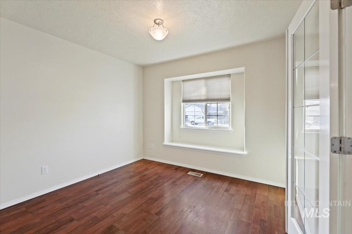 612 Goshawk Avenue Middleton, ID 83644 - Photo 7 of 36 Spare room featuring a textured ceiling and dark wood-type flooring
