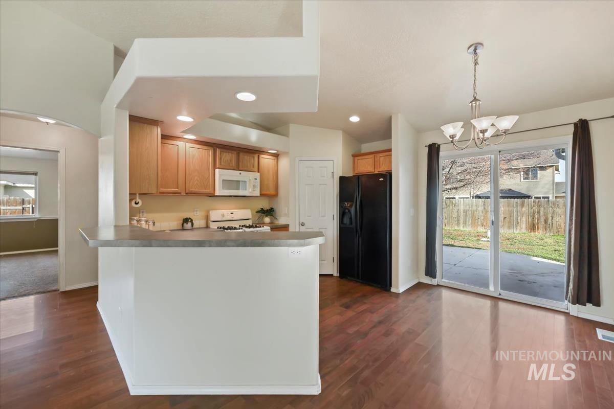 612 Goshawk Avenue Middleton, ID 83644 - Photo 8 of 36 Kitchen featuring a chandelier, white appliances, plenty of natural light, and dark wood finished floors