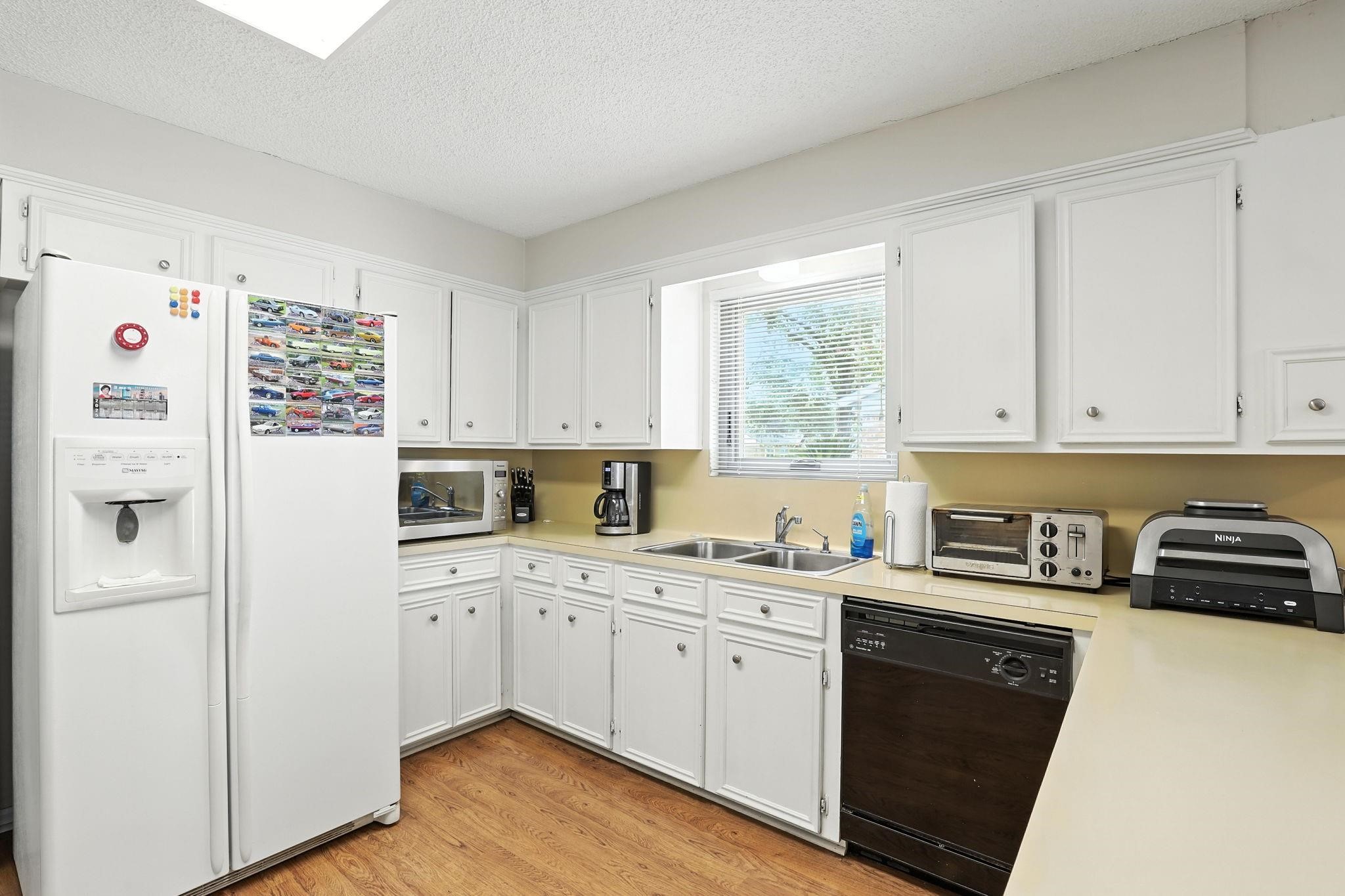 2910 Riata Lane Houston, TX 77080 - Photo 10 of 23 a kitchen with a sink a refrigerator a window and white cabinets