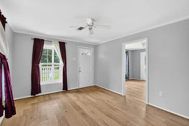 a view of an empty room with wooden floor and a window