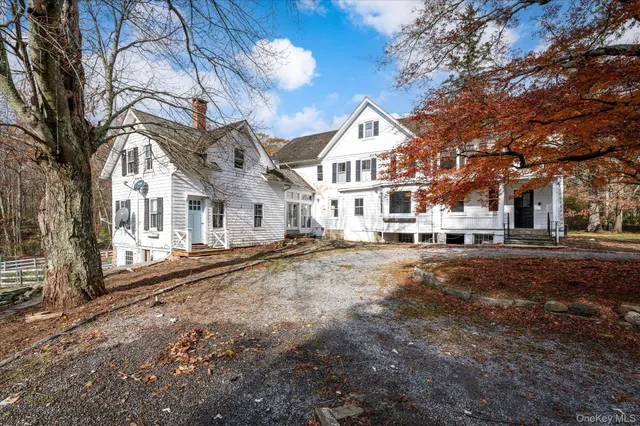 a view of a white house with a yard covered in the forest