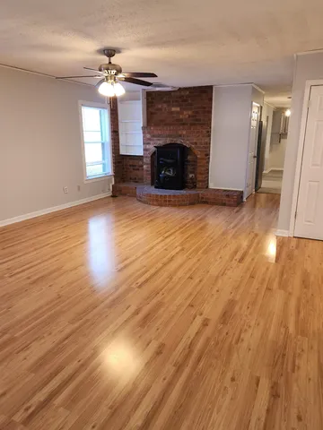 an empty room with wooden floor fireplace and windows