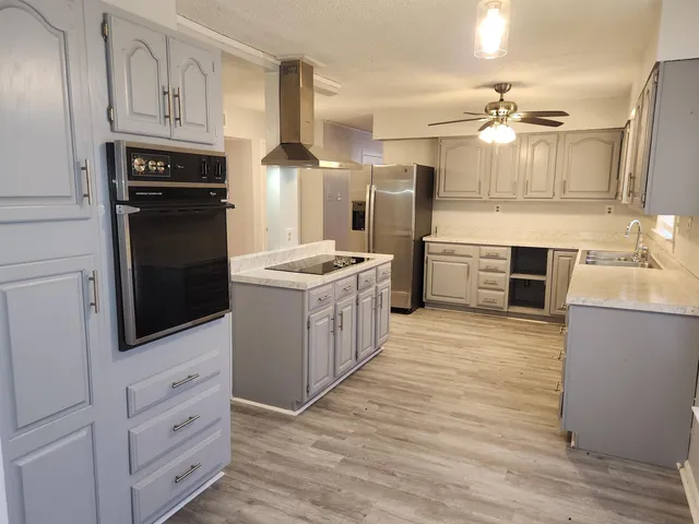 a kitchen with stainless steel appliances a stove top oven a refrigerator a sink and dishwasher with white cabinets