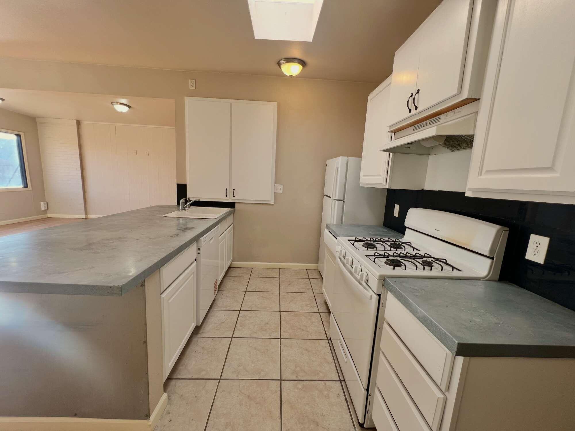 2301 49th Street Lubbock, TX 79412 - Photo 6 of 18 a kitchen with granite countertop a stove a sink and a refrigerator