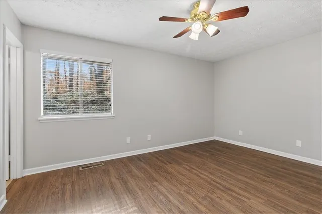 a view of an empty room with window and wooden floor