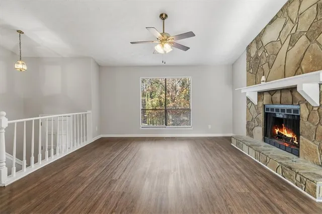 a view of an empty room with wooden floor fireplace and a window