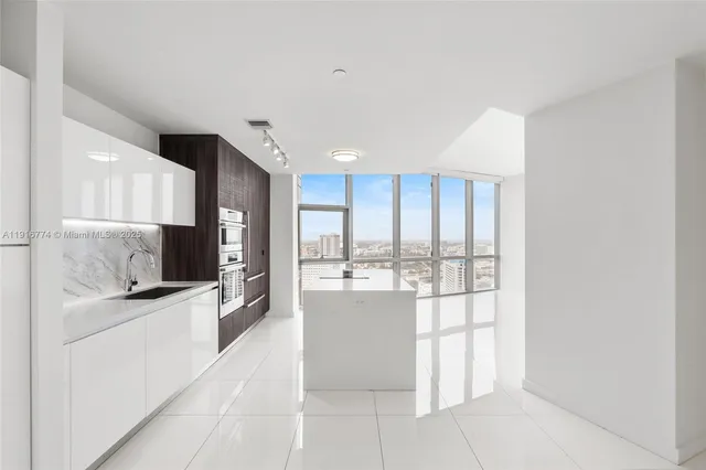 a large white kitchen with a large window