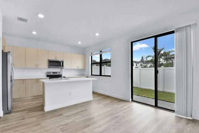 a kitchen with stainless steel appliances granite countertop a refrigerator a sink a stove and a wooden floors