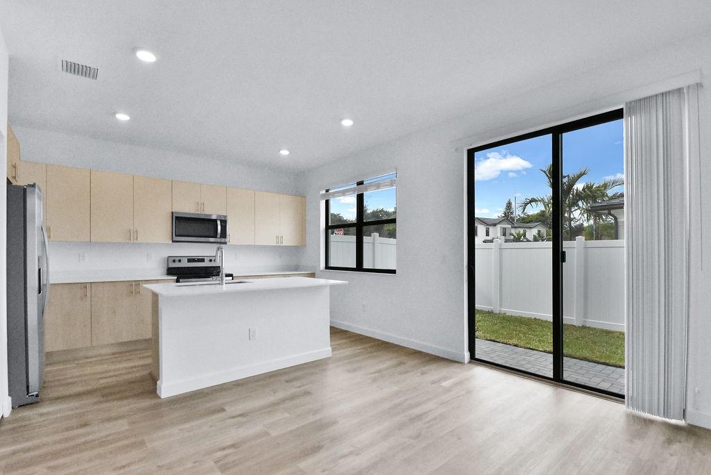 4083 Sunset Way Pompano Beach, FL 33069 - Photo 13 of 34 a kitchen with stainless steel appliances granite countertop a refrigerator a sink a stove and a wooden floors