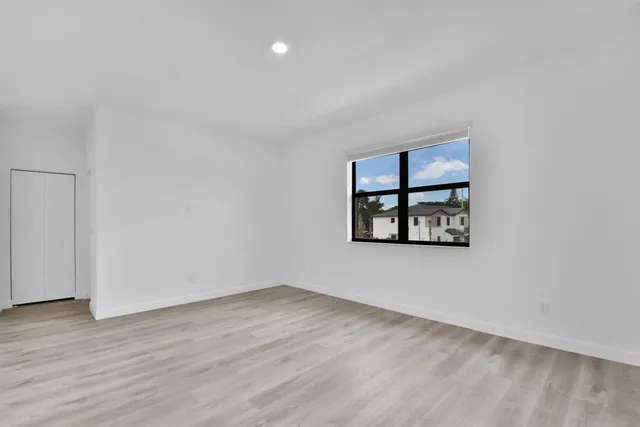 an empty room with wooden floor and window