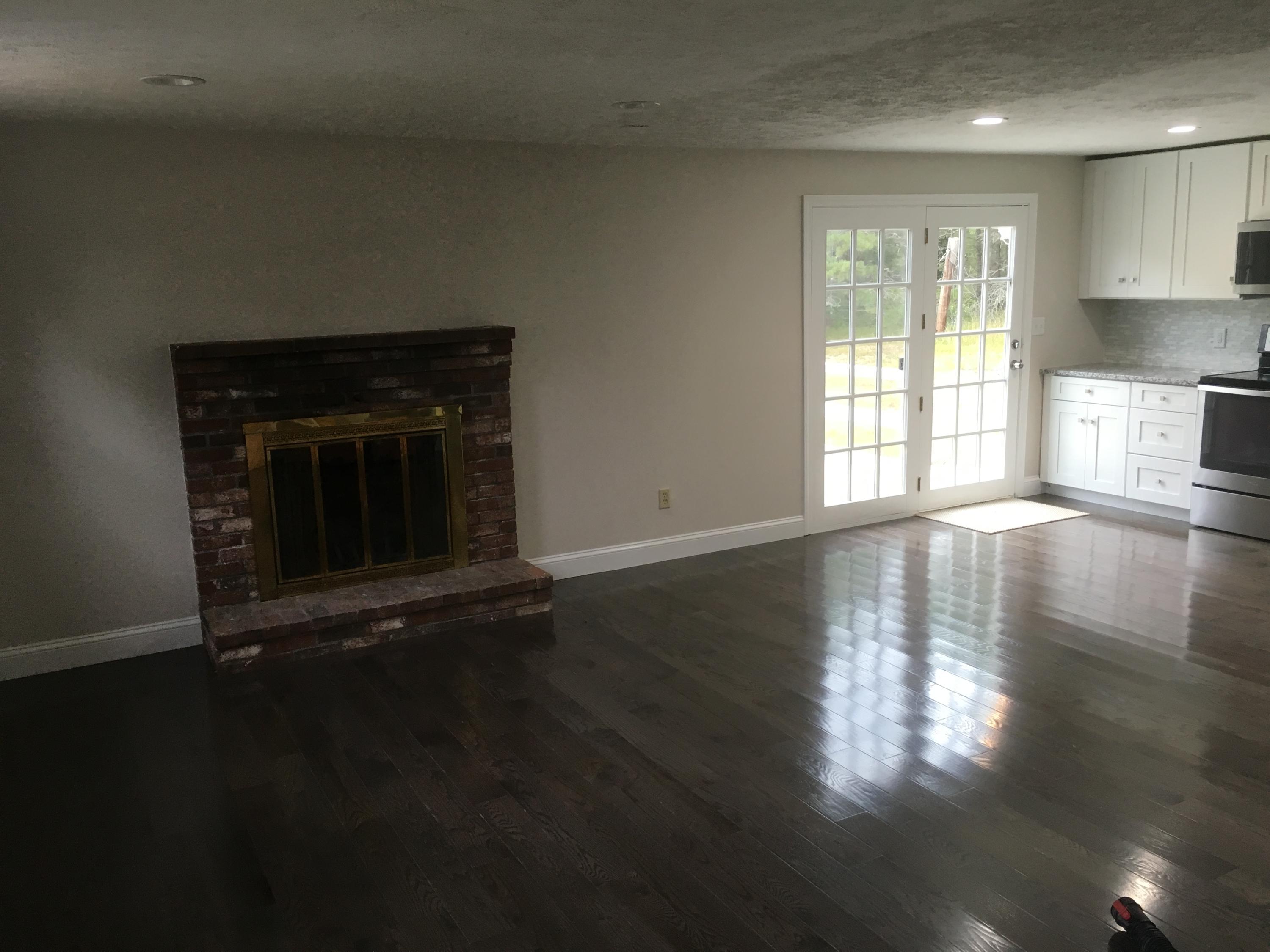 18 Seawood Road Wareham, MA 02571 - Photo 4 of 13 an empty room with wooden floor and fireplace