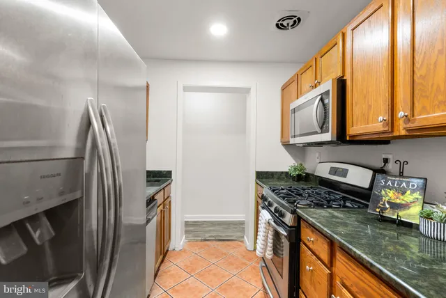 a kitchen with stainless steel appliances granite countertop a refrigerator a stove and a sink