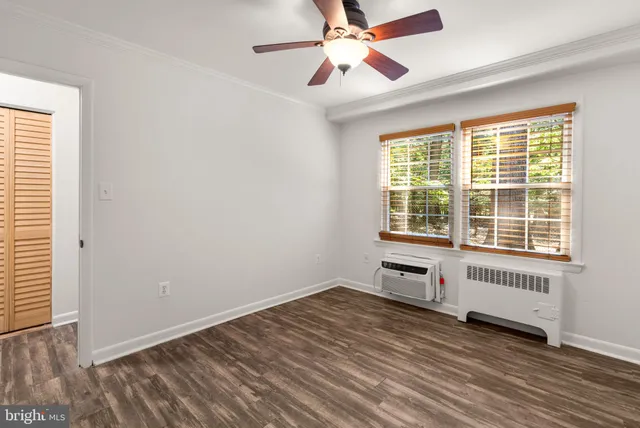 an empty room with wooden floor fan and windows