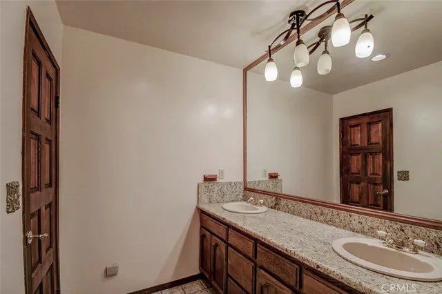 a bathroom with a granite countertop sink a light fixture and a mirror