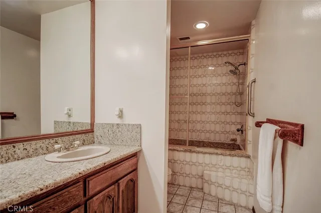 a bathroom with a granite countertop sink a mirror and shower