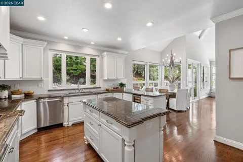 a kitchen with granite countertop stainless steel appliances a stove and white cabinets