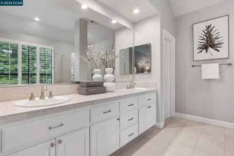 a bathroom with double vanity sink a two mirror a window and a bathtub