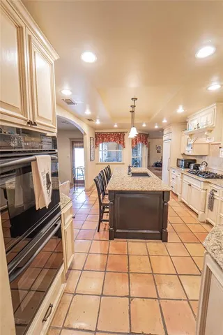 a kitchen with stainless steel appliances kitchen island granite countertop a stove a sink and a microwave