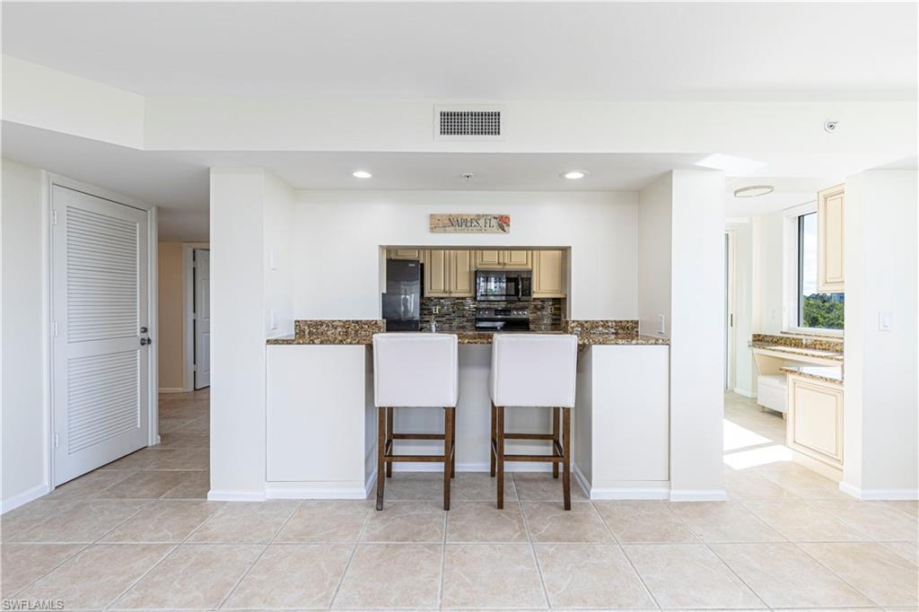 25 Bluebill Avenue, Unit 301 Naples, FL 34108 - Photo 16 of 41 a kitchen with kitchen island white cabinets and stainless steel appliances
