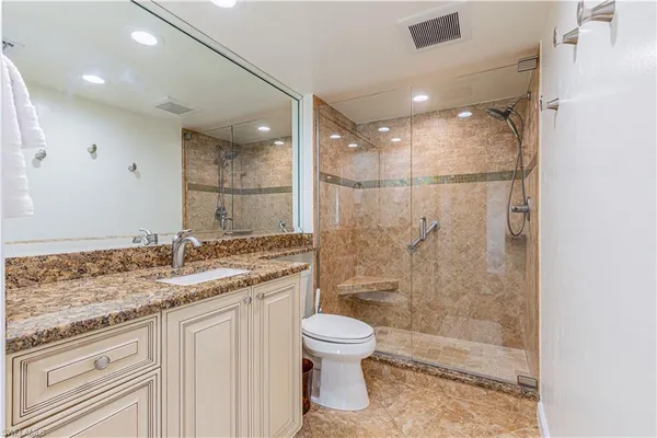 a bathroom with a granite countertop sink a toilet and shower