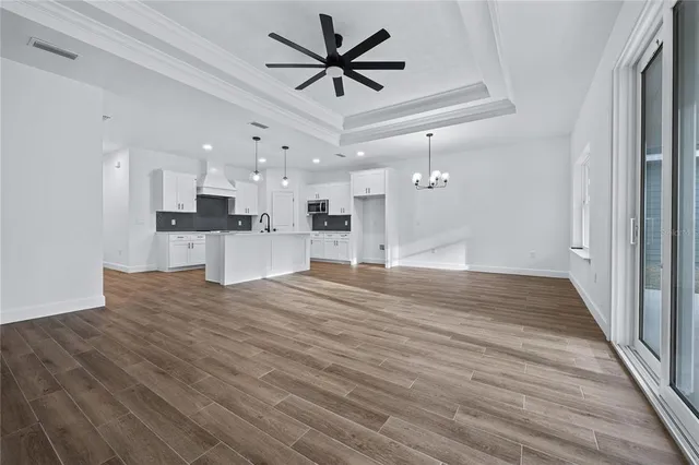 a view of kitchen and empty room with wooden floor